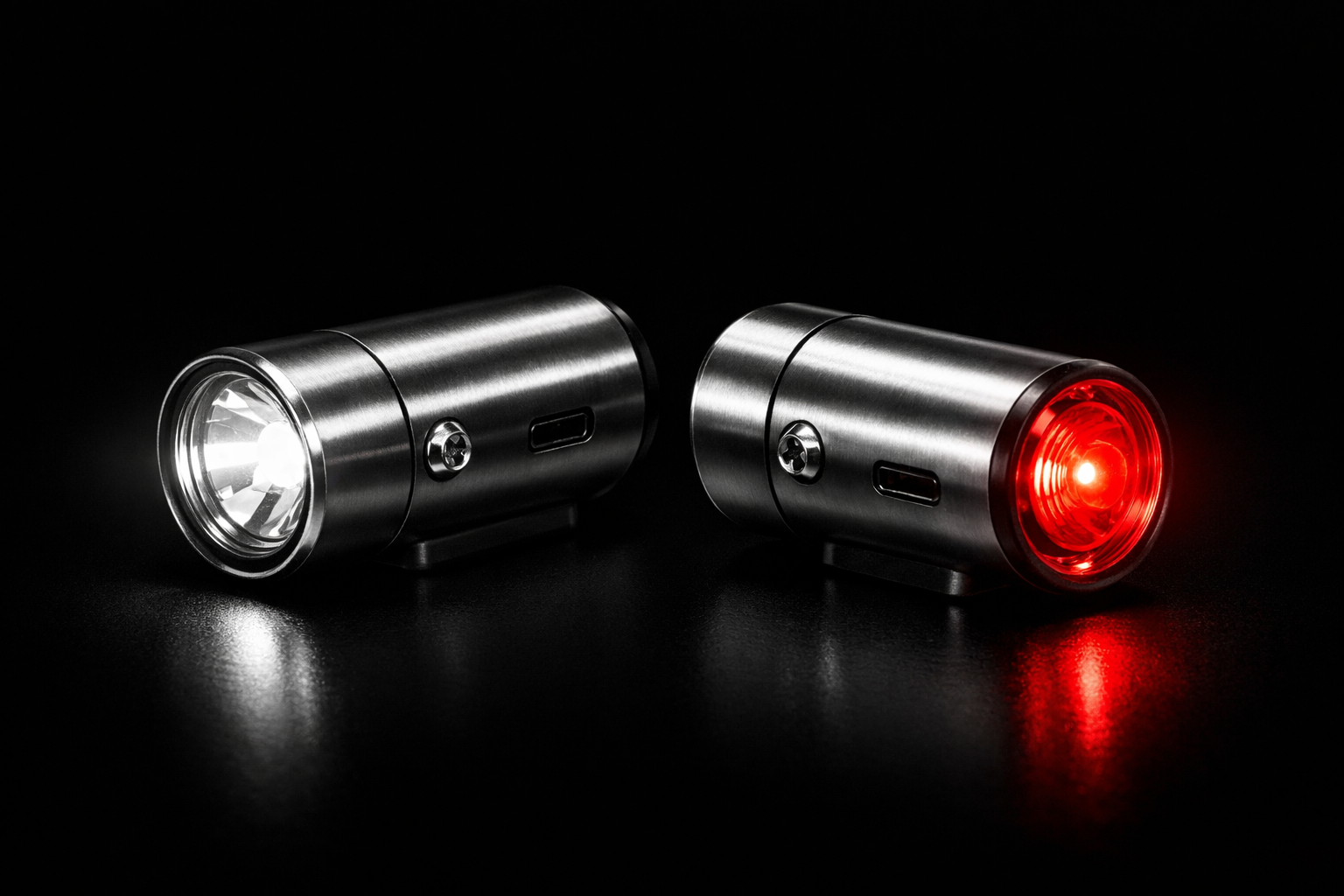 Syla front and rear bicycle lights on a dark background, brushed steel housing catching light